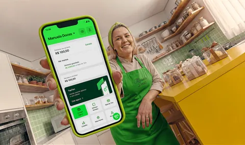 Confeiteira mostrando no celular o app Ton com as vendas a receber
